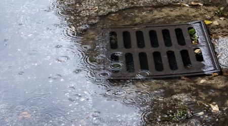 Puddle on street due to clogged drainage system, close-up.