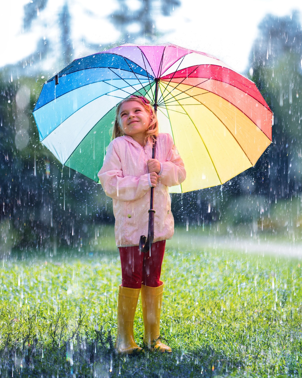 Happy Child With Rainbow Umbrella Under Rain